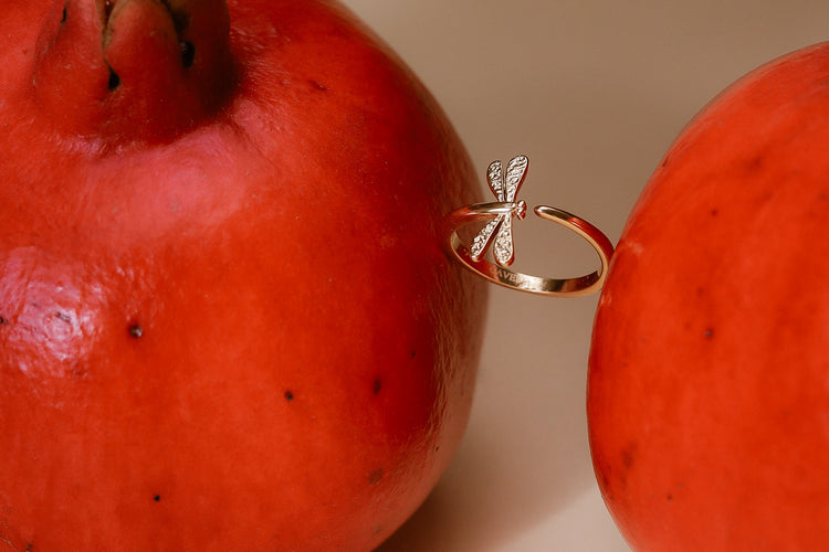Goldener Libellula-Ring zwischen Granatäpfeln